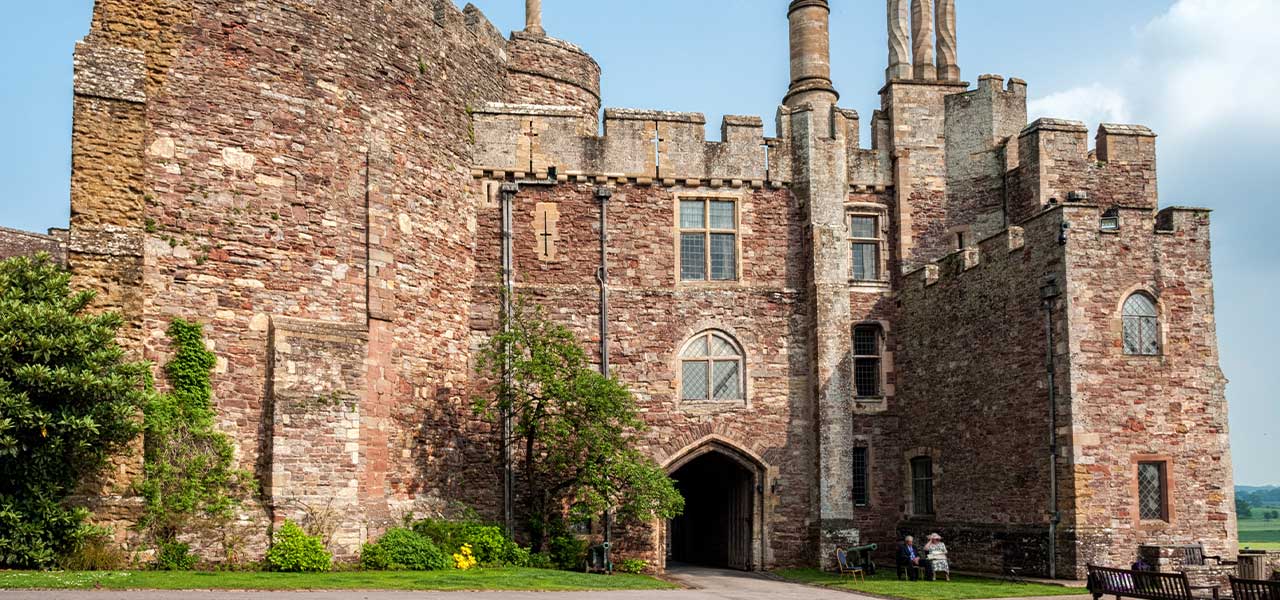 Red sandstone walls and arched gateway of Berkeley Castle in Gloucestershire, a Norman castle visited on the Norman Cotswolds tour