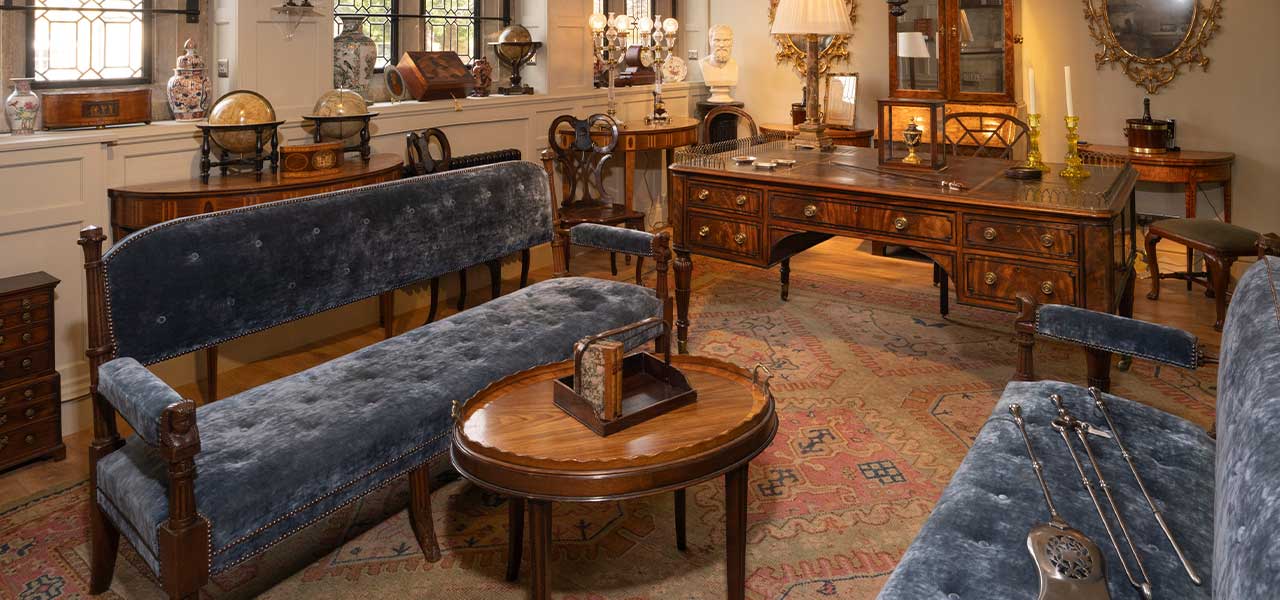 Antiques showroom with mahogany furniture, Persian rugs, oil paintings and green damask armchairs, Cotswolds antiques tour