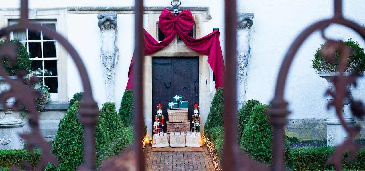 Heritage House front door dressed for Christmas with a red bow, nutcrackers and gift bags, seen through iron gates