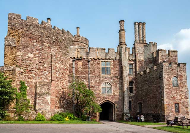 Red sandstone walls and arched gateway of Berkeley Castle in Gloucestershire, a Norman castle visited on the Norman Cotswolds tour